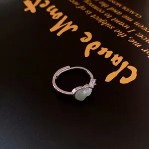 Vintage silver open ring featuring a green jade gourd stone and zircon on a black book