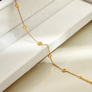 Detailed close-up of golden gear-shaped charms on a luxury minimalist chain bracelet