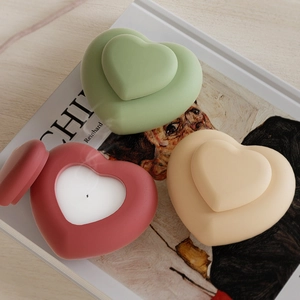 Détail de boîtes à bougies en forme de cœur en rouge, vert et beige mat sur un magazine