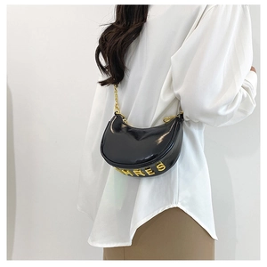 Detail of black crescent moon bag with golden chain strap and polished leather finish