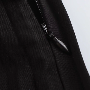 Detailed close-up showing a high-quality invisible zipper on black pleated fabric pants
