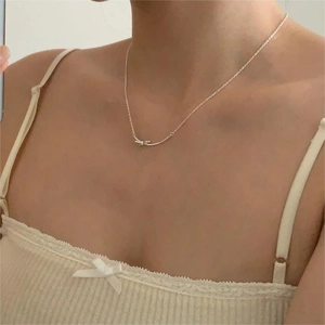 Close-up of model wearing a delicate 925 sterling silver bow knot pendant necklace