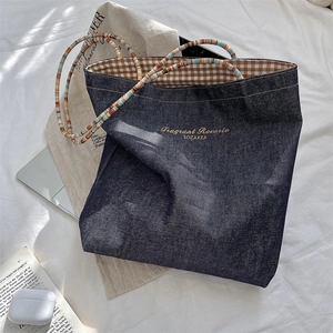 Detail of blue denim tote bag with gold embroidery and colorful beaded handles
