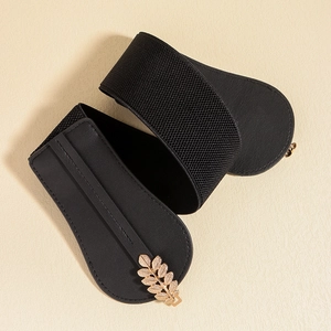 Detail of elegant gold leaf buckle on a black elastic waist belt for women's dresses