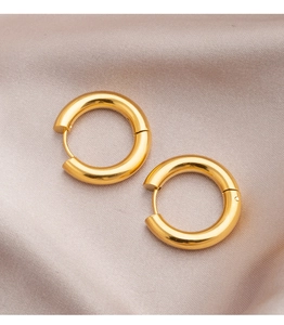 Macro shot of thick gold hoop earrings with polished metal finish on satin silk