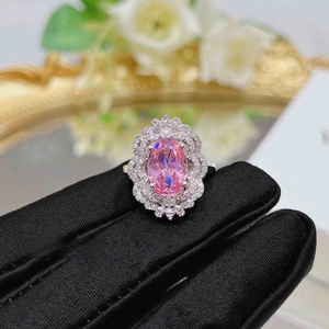Macro shot of pink oval gemstone ring with multi-layer zircon floral halo on silver band