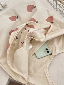 Off-white canvas tote bag with peach print showing functional inner pocket and smooth texture