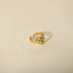 Detail of gold chain-style open ring featuring a blue and white checkered heart charm