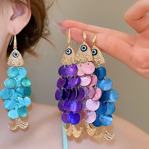 Detail view of fish-shaped earrings featuring colorful shell sequins and golden metal