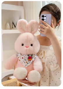 Detail of a pink plush bunny wearing a floral scarf held by a model in warm light
