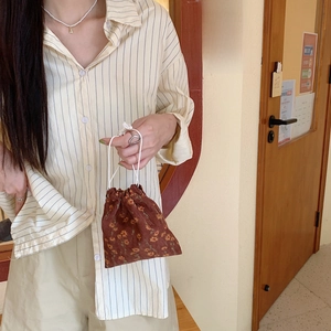 Detailed texture of brown corduroy drawstring pouch with yellow floral pattern