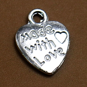 Vista macro del colgante de corazón plateado con grabado Made with Love para joyas DIY