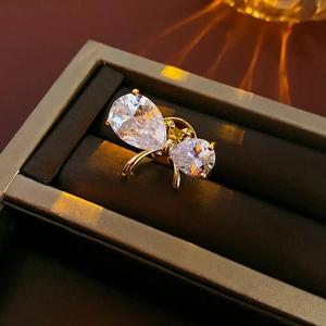 Close-up of a gold-plated bow brooch with teardrop zircons in a dark jewelry box
