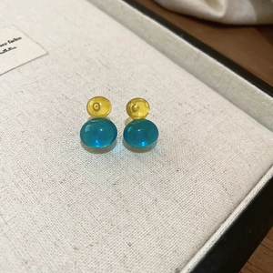 Detail of yellow and lake blue translucent beaded earrings on a white fabric display