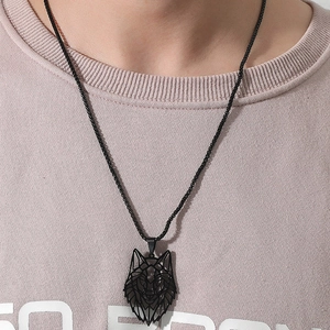 Close-up of a black geometric hollow wolf head pendant on a black woven cord necklace