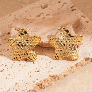Gros plan de boucles d'oreilles étoiles dorées avec texture losange sur pierre