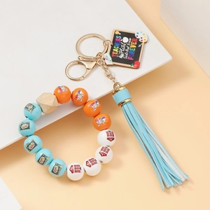 Detail of beaded teacher keychain with wooden charm and blue tassel on a light background