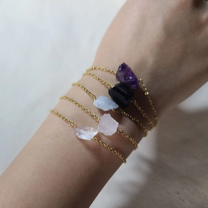 Detailed view of layered stainless steel bracelets with irregular raw natural crystals