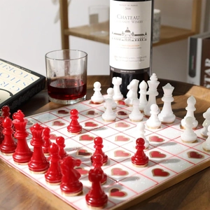 Détail d'un échiquier avec motifs cœurs et pièces en résine rouge et blanc sur plateau