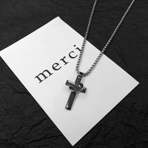 Macro view of a stainless steel cross necklace with a ring pendant and engraved details