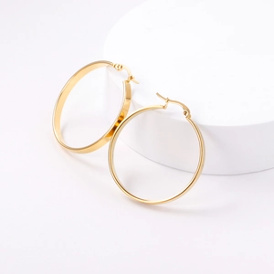 Detailed view of glossy gold geometric hoop earrings on a minimalist white display
