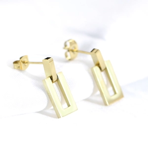 Detailed view of gold-plated stainless steel hollow rectangular drop earrings on fabric
