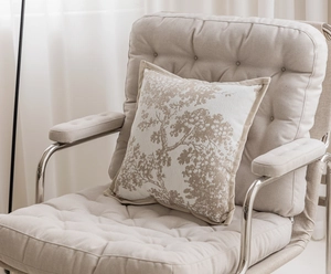 Detail of beige cushion cover with light brown tree pattern on a soft armchair