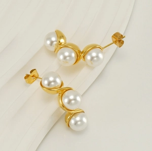 Detail shot of three white pearls in a wave-like gold setting on a stainless steel earring