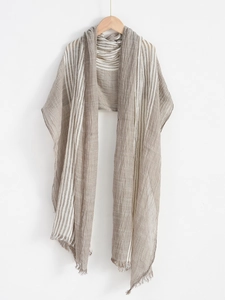 Detail of beige striped lightweight scarf with crinkle texture and fringe on a hanger