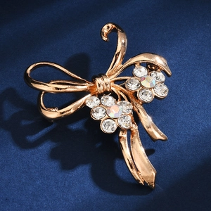 Macro shot of elegant golden bow brooch with sparkling rhinestones on dark blue velvet