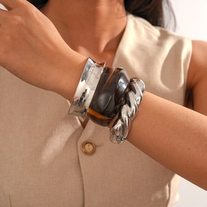 Detail of silver metallic and brown resin bracelets on model with a minimalist look