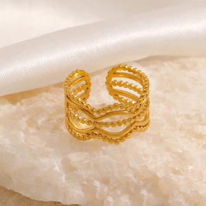 Adjustable gold wave ring with beaded lines on a textured stone base and silk backdrop