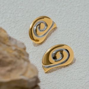 Orecchini a spirale minimalisti in finitura bicolore oro e argento su sfondo in pietra