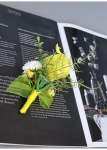 Detail of yellow rose boutonniere with green ribbon bow on a dark magazine background