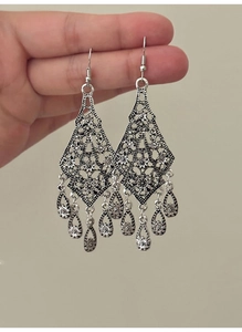 Detail of vintage bohemian teardrop tassel earrings with intricate hollow flower patterns
