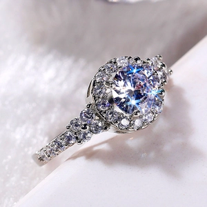 Macro shot of silver ring with halo-set round zircon and floral cluster diamond band