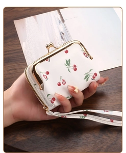 Close-up of white cherry pattern coin purse with gold clasp and matching wrist strap