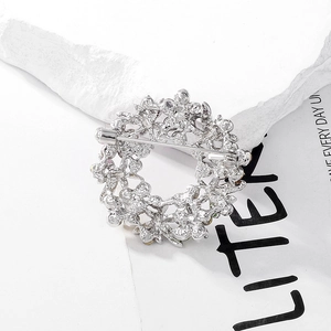 Silver dragonfly floral wreath brooch back view with safety pin on textured stone