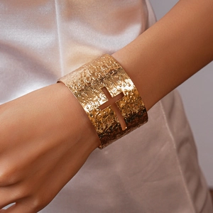 Detailed view of wide hammered gold-plated open cuff bracelet with hollow cross pattern