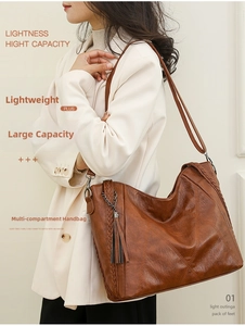 Detail view of large brown faux leather tote with quilted texture and tassel charm