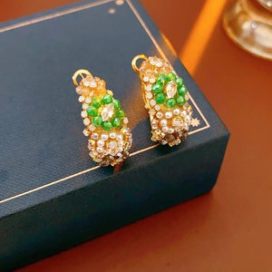 Macro detail of vintage gold hoop earrings with green beads and pearls on jewelry box