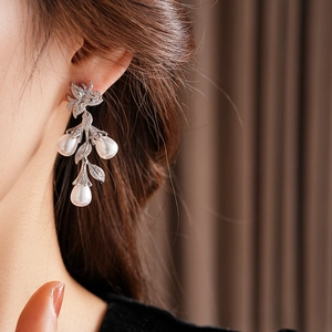 Gros plan détaillé de boucles d'oreilles vintage en argent avec fleurs et perles sur le modèle