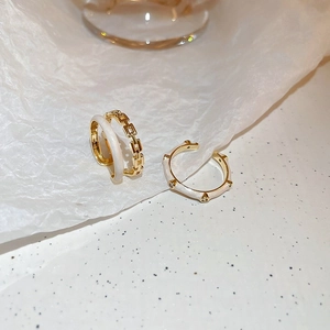 Close-up of golden geometric ring with cream enamel and sparkling zircon details