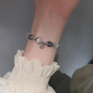 Detailansicht des Opal-Perlenarmbandes mit Silberanhänger am Handgelenk einer Frau