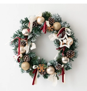 Close-up of snowy pine needles with gold ornaments and natural cones on a Xmas wreath
