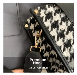 Detail of golden metal hook and black leather edge on houndstooth pattern tote bag