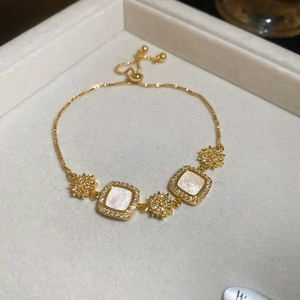 Gros plan d'un bracelet en or avec nacre carrée et détails en zircon étoilé
