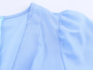 Detail of light blue embroidered dress featuring puff sleeves and refined seam stitching