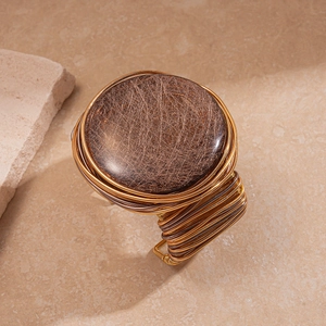 Macro detail of gold and coffee resin cuff with intricate woven metal wire textures