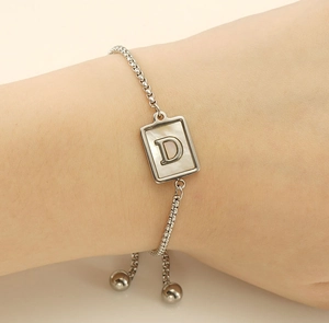 Detail of silver stainless steel bracelet with square shell pendant and letter D engraving